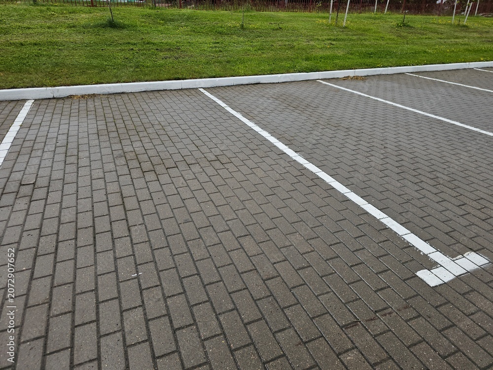 Obraz premium Parking lot has empty spaces during day near grassy