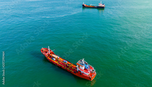 Foto Aerial perspective of an orange chemical tanker ship navigating through green oc