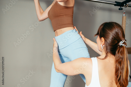 Obraz na płótnie A woman lifts weights while another woman assists her in a gym
