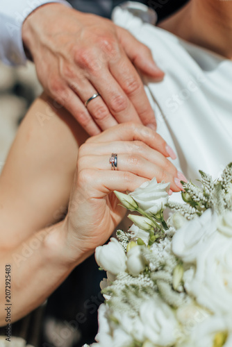 Fotografie Close-up of newlyweds showing wedding rings, with hands gently touching near a w