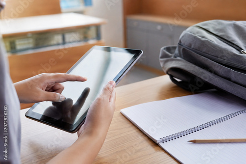 A student using a digital tablet for e-learning in a classroom setting.