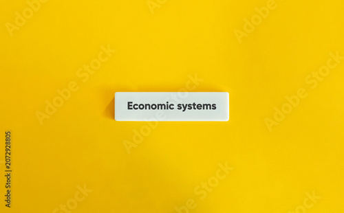 Economic systems concept block on yellow background