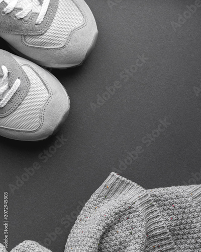 Grey athletic sneakers and knitted sweater on dark background, fashion clothing and footwear concept