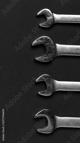 Set of metal open end wrenches arranged in row on dark surface. Mechanical tools for DIY repairs and professional construction work