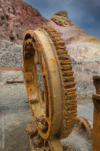 Rusty and abandoned industrial wheel. Remains of the sulphur mining at volcanic White Island, rough, barren landscape with rocks and lava in the crater