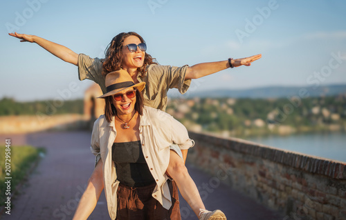 Foto Happy young lesbian couple having fun with a piggyback ride on a sunny summer da