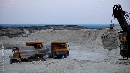 Huge mining dump truck moving stones in an open-pit quarry against a blue sky background