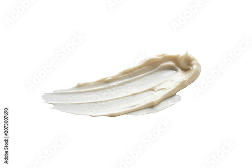 A thick smear of light beige cosmetic cream or lotion with a smooth texture and visible ridges isolated on a plain black background surface