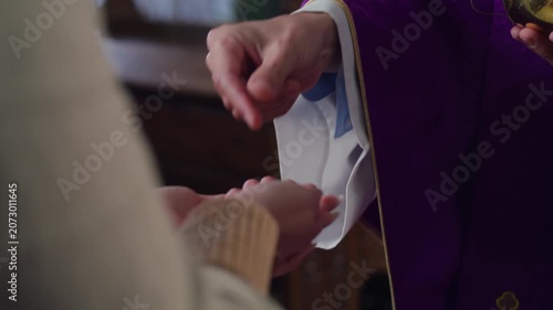 Receiving Holy Communion in the Catholic Church, a priest giving the Eucharist host into the hand of a female worshipper.