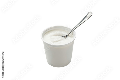 A white plastic cup filled with creamy yogurt and a silver metal spoon inside, isolated on a white background, for food needs