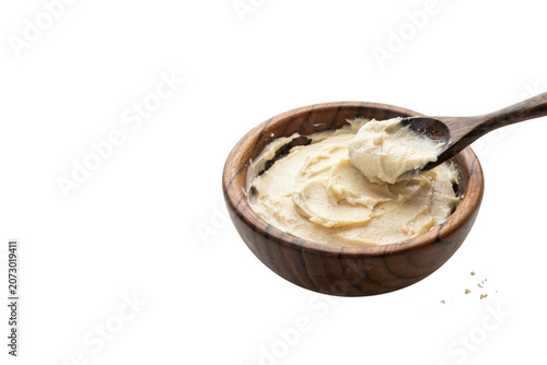 A wooden bowl filled with creamy beige hummus being scooped by a dark wooden spoon, isolated on a solid black background, for food