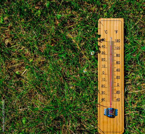 Fotografía Wooden thermometer on dry, parched green grass showing high temperature during an extreme summer heatwave and drought