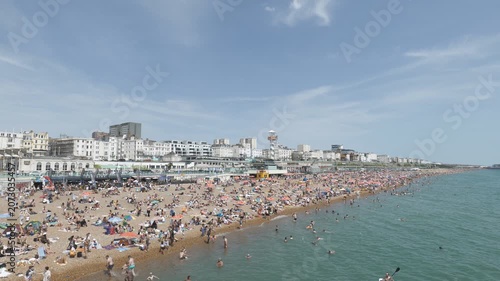 A crowded beach filled with people next to a city skyline.