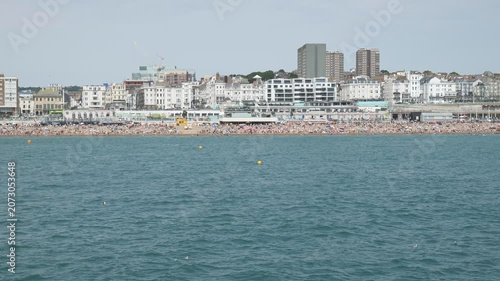 A crowded beachfront with buildings viewed from the water.