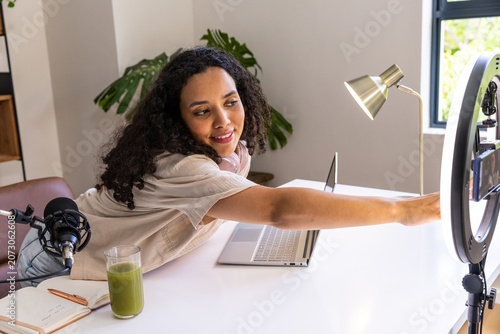 Foto African American woman leaning forward tweaking ring light and phone at home off