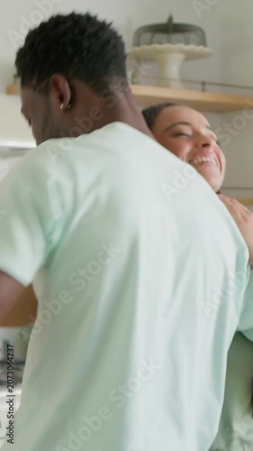 Vertical video: Turning woman reaching partner's hand in kitchen, couple dancing by frying pan