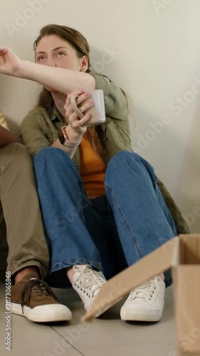 Vertical video: Reaching woman in green top pointing upward during move at home, holding mug by box