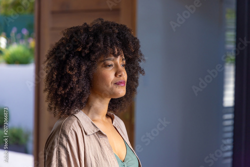Obraz na plátně African American woman standing gazing out doorway at home wearing beige shirt a