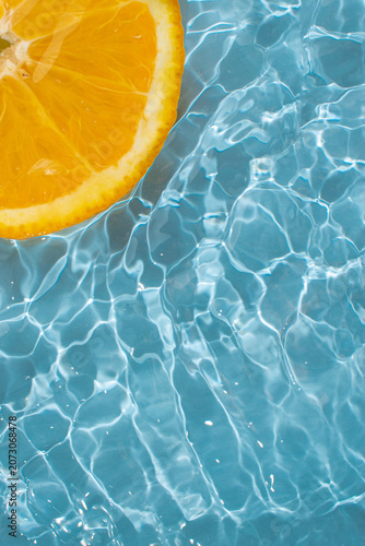 Blue wave water with slice of orange on the background, creative ripple texture style. Vertical tropical summer water background.	