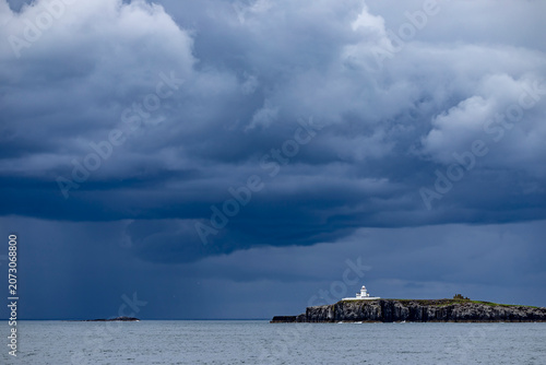 Fotografie A thundercloud over the sea and an island with a lighthouse