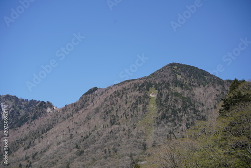Takayama, Japan - May 10 2026 - Majestic green mountain slope under clear blue sky