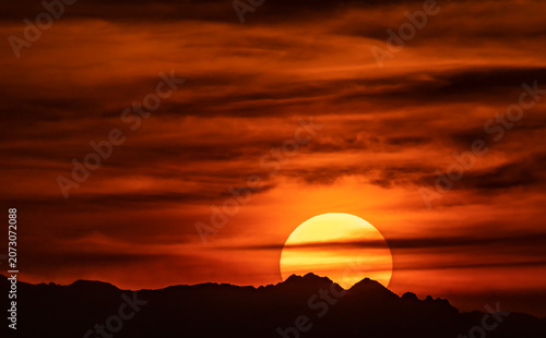The sun's disk at sunset behind the mountains