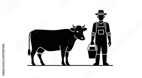 Farmer stands next to a dairy cow while holding a metal bucket for morning milking duties.