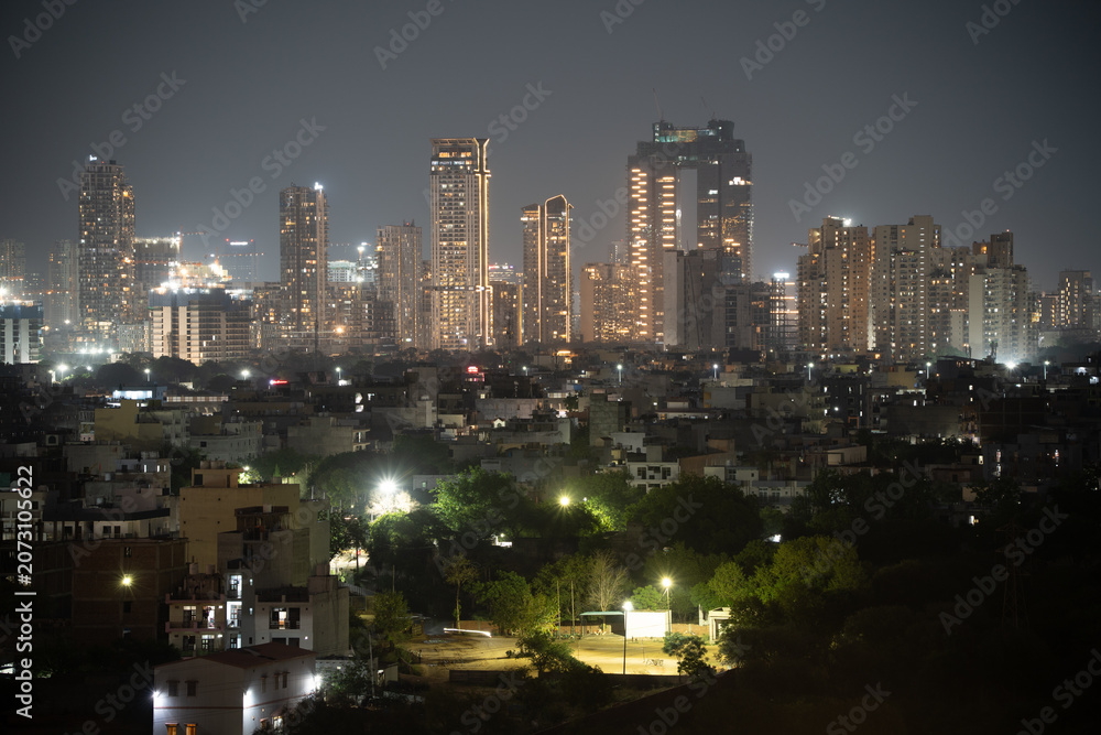 Fototapeta premium Aerial drone wide shot showing cityscape skyscrapers at night in mumbai hyderabad bangalore with smaller houses in foreground