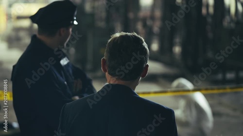 Police officer and detective discussing murder investigation at crime scene