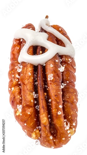 A close-up of a single brown nut with white icing and sugar