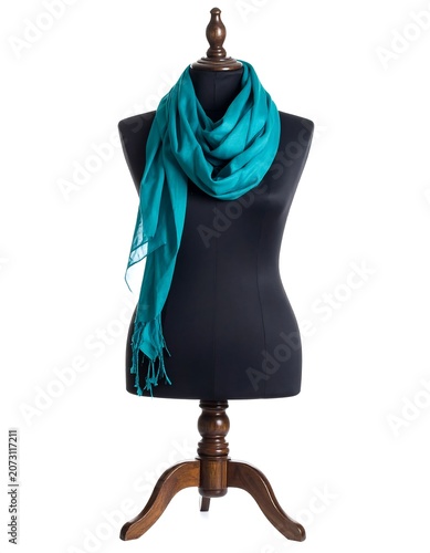 A black dress form with a vibrant blue scarf draped around its neck on a wooden stand against a white background