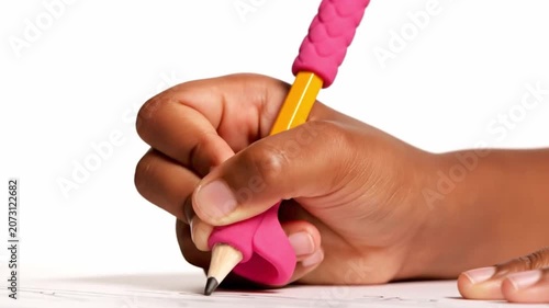 Child-sized hand grips short yellow pencil with bright pink ergonomic sleeve, tip touching white paper while making steady mark in bright tabletop close-up, with soft shadows, clean background,