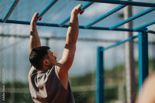 Foto A young man grips blue monkey bars while performing an upper-body exercise