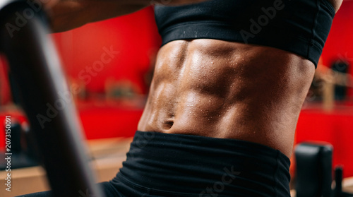 Athletic person performing core exercise showing strong abdominal muscles in red room