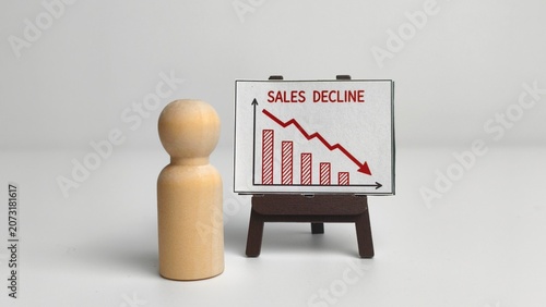 Photos Business crisis and financial loss concept with a wooden peg doll standing next to a chart showing a sales decline