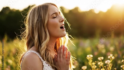Three-quarter profile of young blonde woman standing in wildflower meadow, eyes closed, hands clasped near chin, lips softly parted, glowing sunlight, gentle breeze, serene contemplative mood
