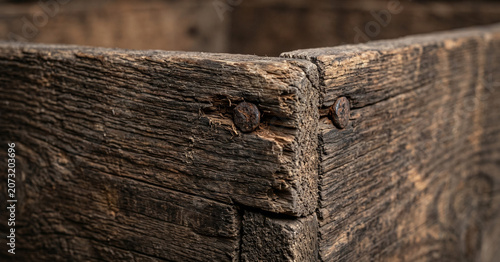 Macro view of aged weathered wooden crate with rusted nails and deep grain texture