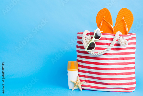 Stylish bag with beach accessories . Summer holiday concept. Top view of beach bag with sunscreen cream with space for text