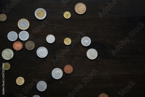 Many international coins from different countries scattered on dark textured table, global finance concept
