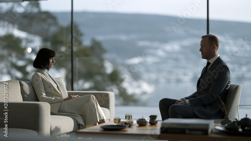 Moroccan and Norwegian diplomats sharing mint tea ceremony in a glass pavilion overlooking a snowy fjord, cultural objects blending on a low cedar table, ideal for international