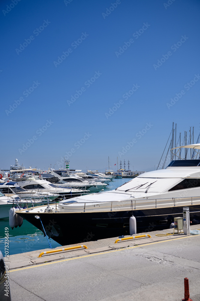 Fototapeta premium Luxury yachts and motorboats moored at the pier in Alanya marina. Mediterranean sea resort, nautical transportation, summer vacation travel and coastal tourism business concept in Turkey, investment