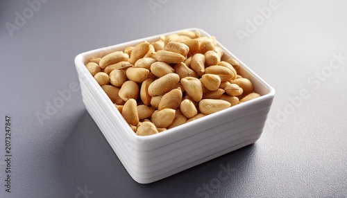 a square white container overflowing with shelled golden peanuts