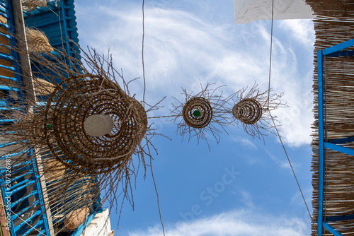 Traditional handmade palm frond lampshades hanging against a blue sky