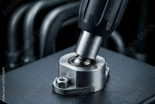 Macro eye-level focus on hydraulic joystick interface. strong key light sculpts geometric volume, revealing micro abrasions, orbital sanding marks, and greasy sheen on swiveling ball joint.
