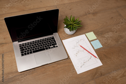 Photography Laptop computer with printed stock market charts and financial reports