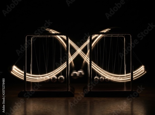 Long exposure of Newtons cradle balls creating glowing motion trails.