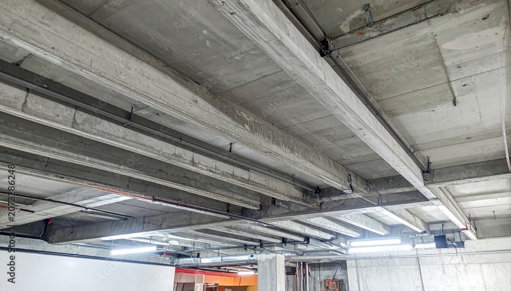 Obraz premium Reinforced concrete basement ceiling showcasing robust structural beams and protective layers, essential for modern building infrastructure.