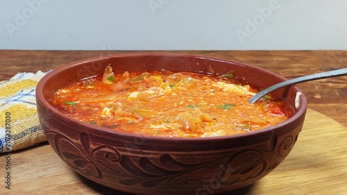 Red borscht seasoned with sour cream in bowl, side view