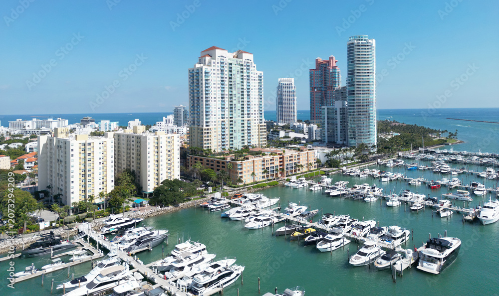 Obraz premium Aerial view of Miami Beach with marina, yachts and coastal. Miami Beach coastal skyline with boats. Miami Beach cityscape with marina port. Coastal cityscape of Miami Beach with yachts and harbor.