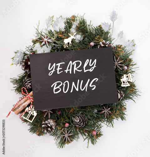 Wreath decorated with pine cones, festive ornaments, and a chalkboard sign displaying yearly bonus, creating a cheerful holiday atmosphere for Christmas and New Year celebrations